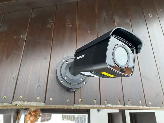Černá kamera Hikvision na dřevěném podhledu