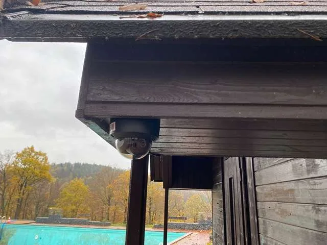 Kupolová kamera pod střechou dřevěné budovy s výhledem na koupaliště
