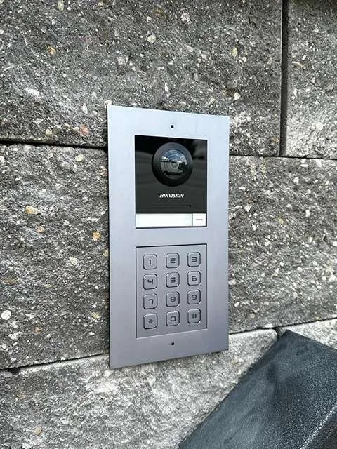 Venkovní stanice videotelefonu Hikvision s číselnou klávesnicí v kamenné zdi