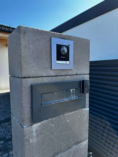 Venkovní stanice videotelefonu ve sloupku oplocení nad poštovní schránkou